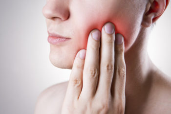 tempromandibular joint pain, person holding jaw in pain